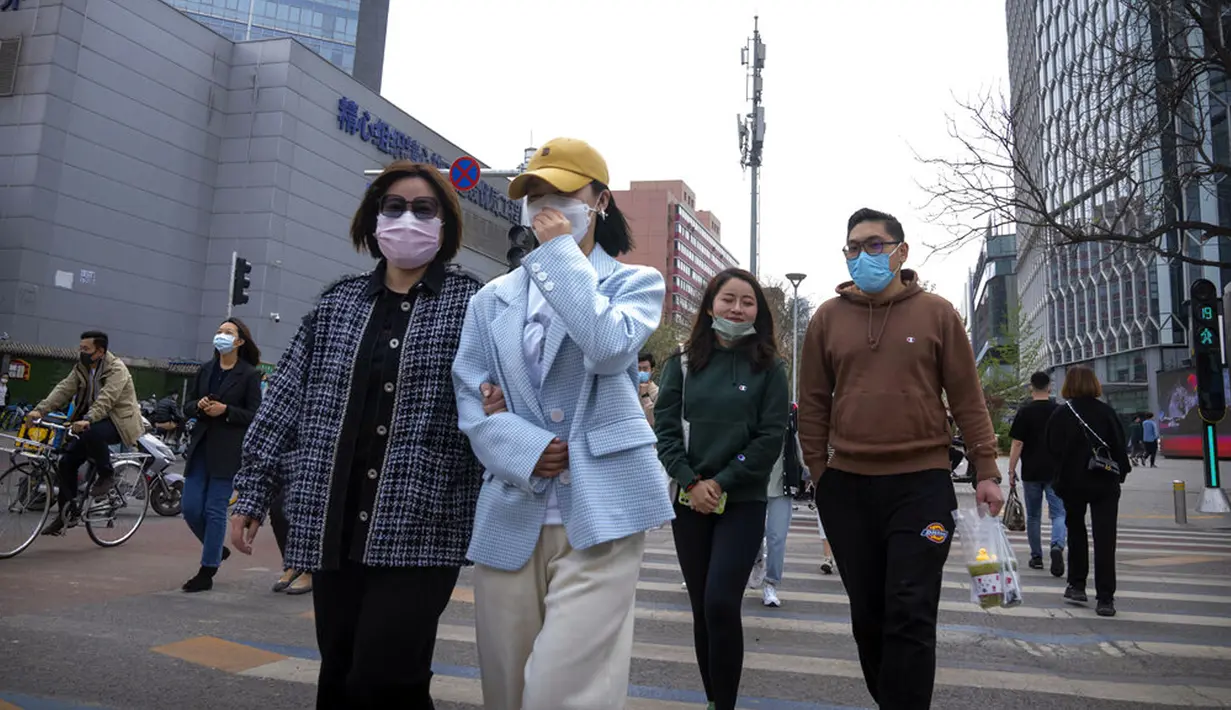 Orang-orang yang memakai masker berjalan melintasi persimpangan di Beijing, China, 13 April 2022. Shanghai bergerak untuk lebih melonggarkan lockdown di kota terbesar di China tersebut yang tampaknya terhenti. (AP Photo/Mark Schiefelbein)