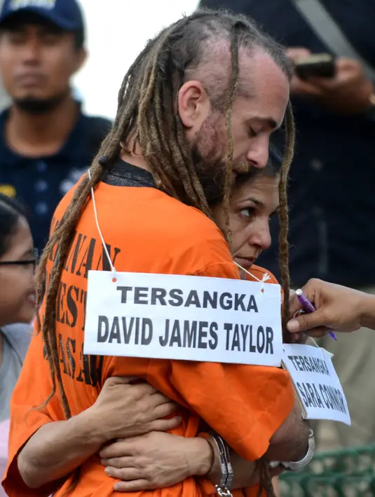 Pasangan kekasih berkewarganegaraan Australia dan Inggris Sara Cannor dan David James Taylor saling berpelukan selama proses rekonstruksi kasus pembunuhan polisi, Aipda Wayan Sudarsa, di Pantai Legian, Kuta, Rabu (31/8). (AFP PHOTO / SONNY Tumbelaka)