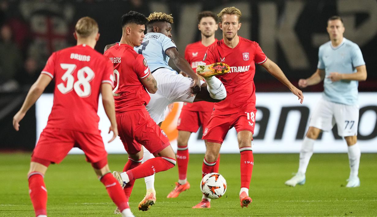 Pemain Twente, Mees Hilgers (kedua kiri) berebut bola dengan pemain Lazio, Fisayo Dele-Bashiru dalam laga lanjutan Liga Europa 2024/2025 yang berlangsung di De Grolsch Veste stadium, Enschede, Belanda, Jumat (25/10/2025) dini hari WIB. (AP Photo/Peter Dejong)