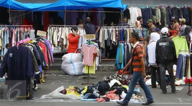 Pedagang menjajakan pakaian bekas di kawasan Pasar Senen, Jakarta, Senin (23/1). Pascakebakaran beberapa hari lalu, para pedagang terpaksa berjualan di luar gedung, meskipun menutup jalan dan mengganggu arus lalu lintas. (Liputan6.com/Immanuel Antonius)