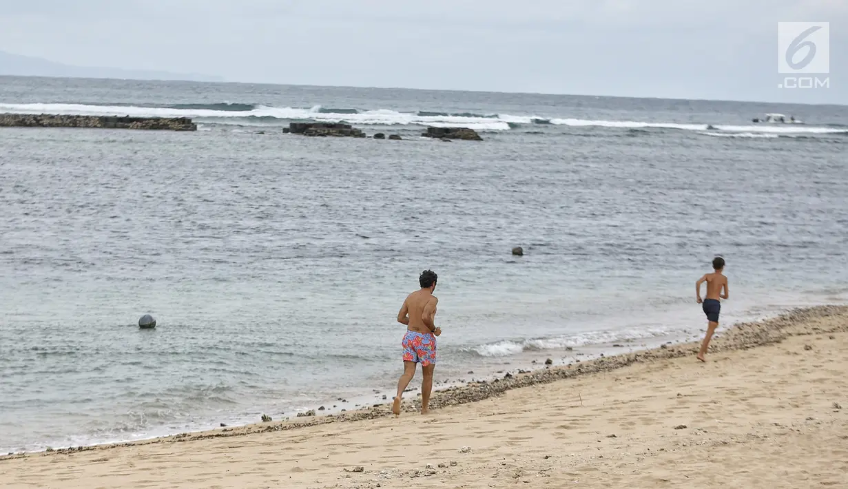 Wisatawan asing berlarian di tepi Pantai Nusa Dua, Bali setelah gempa bumi, Senin (6/8). Aktivitas pantai Nusa Dua Bali masih ramai wisatawan asing setelah adanya gempa 7 pada skala richter yang berpusat di Lombok NTB. (Liputan6.com/Faizal Fanani)