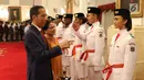 Presiden Joko Widodo (kiri) menunjuka ke arah anggota Pasukan Pengibar Bendera Pusaka (Paskibraka) usai pengukuhan di Istana Negara, Jakarta, Kamis (15/8/2019). Sebanyak 68 anggota Paskibraka tersebut akan bertugas pada upacara HUT ke-74 RI. (Liputan6.com/Angga Yuniar)