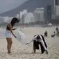 Dua wanita memungut sampah dari pantai Copacabana pada Hari Laut Sedunia di Rio de Janeiro, Brasil, Rabu (8/9/2022). Organisasi Route Brasil menyerukan agar orang-orang berkumpul untuk acara yang diberi nama "Pelukan Itu," dan untuk memungut sampah di pantai, untuk menarik perhatian pada pencemaran laut. (AP Photo/Silvia Izquierdo)