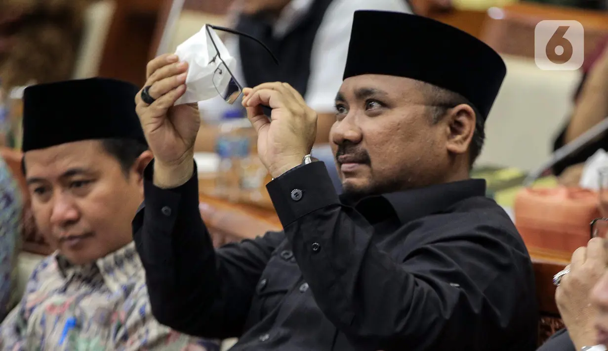 Menteri Agama Yaqut Cholil Qoumas membersihkan kaca mata saat membahas draft penetapan biaya haji 2023 dalam rapat panja bersama Komisi VIII DPR RI di kompleks Parlemen, Senayan, Jakarta, Rabu (15/2/2023). Pemerintah bersama legislator menyepakati biaya haji yang harus dibayarkan jemaah sebesar Rp 49.812.700. Angka itu disepakati dalam rapat Panja yang dgelar di Kompleks Parlemen, Jakarta, Rabu (15/2). (Liputan6.com/Faizal Fanani)