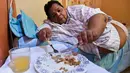 Oscar Vasquez Morales (44) saat makan siang di rumahnya di Palmira, Kolombia, 19 Maret 2016. Dengan bobot tubuh hampir 400 kg, Oscar membutuhkan bantuan orang lain untuk melakukan berbagai kegiatannya sehari-hari. (AFP PHOTO/Luis ROBAYO)