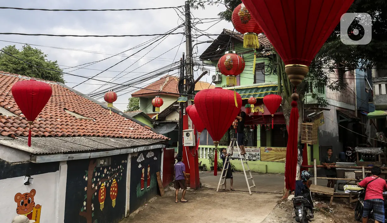 Warga menghias jalan dengan lampion di Kampung Limo, Depok, Jawa Barat, Rabu (26/1/2022). Kampung dengan sejumlah warga keturunan Tionghoa tersebut menyambut perayaan Tahun Baru Imlek 2022 dengan menghias gapura dan jalan dengan pernak-pernik Imlek. (Liputan6.com/Johan Tallo)