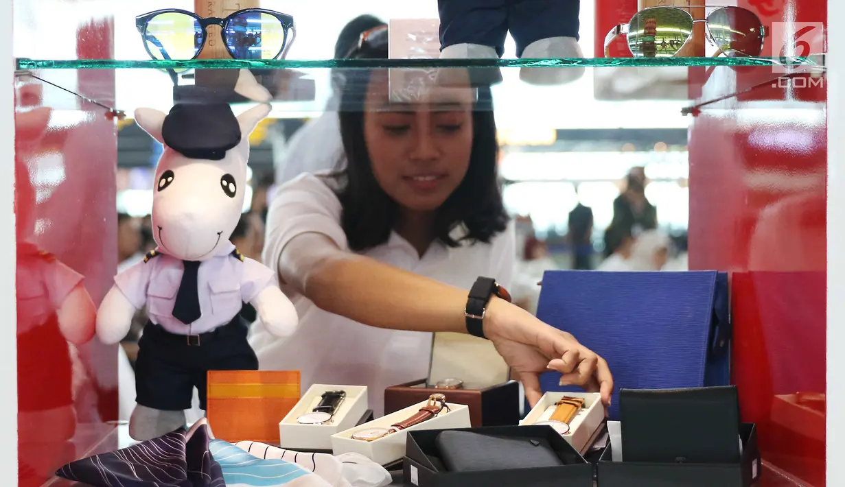 Model menata barang-barang yang dipamerkan di GarudaShop Bandara T3 Soekarno-Hatta, Tangerang, Banten, Selasa (13/2). Barang-barang tersebut bisa dibeli di channel GarudaShop yang ada di website JD.ID. (Liputan6.com/Angga Yuniar)