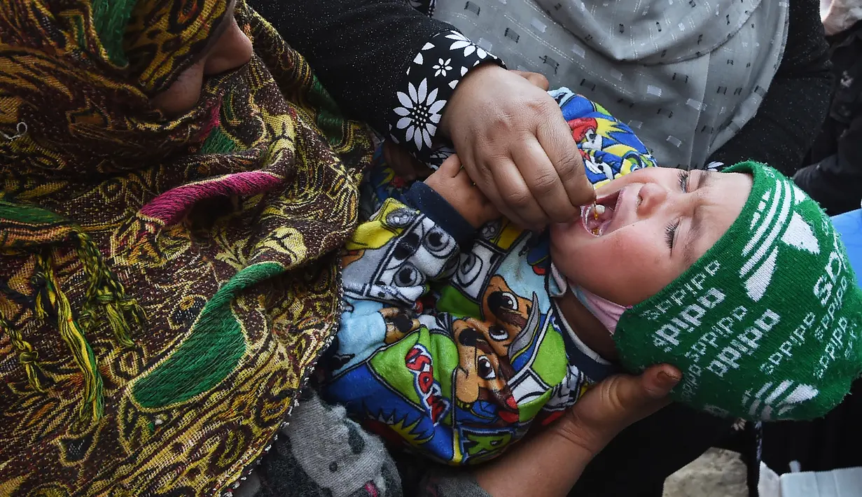 Tenaga kesehatan memberikan vaksin polio kepada seorang balita selama kampanye vaksinasi di kawasan tua Kabul, Afghanistan pada 8 November 2021. Vaksinasi tersebut merupakan yang pertama sejak Taliban berkuasa di Afghanistan. (WAKIL KOHSAR / AFP)