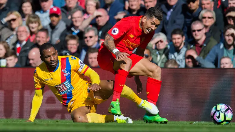 Striker Crystal Palace, Jason Puncheon (kiri), terjatuh saat berduel dengan penyerang Liverpool, Roberto Firmino pada laga di Anfield, Minggu (23/4/2017). 