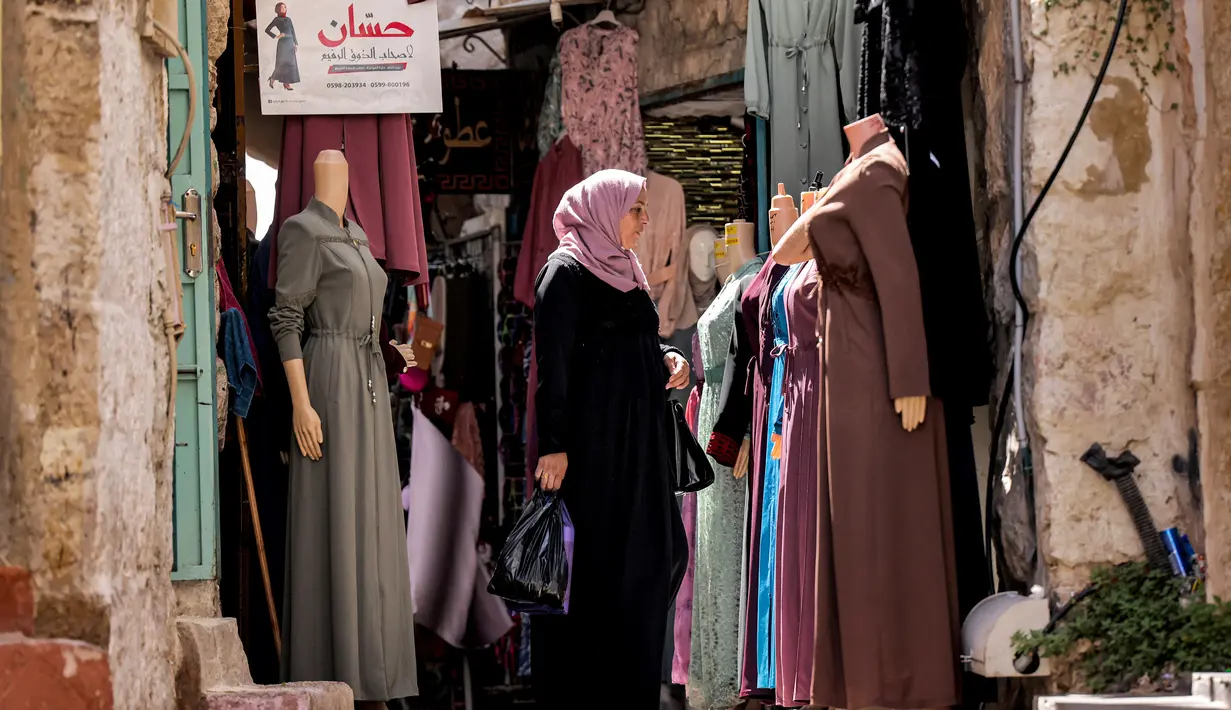 Seorang wanita berbelanja pakaian di pasar di kota tua Betlehem di Tepi Barat yang diduduki (14/9/2021). Penurunan bantuan asing, dengan ekonomi di Tepi Barat dan Gaza berkontraksi sebesar 11,5 persen pada tahun 2020, Otoritas Moneter Palestina melaporkan pertengahan Agustus. (AFP/Emmanuel Dunand)