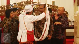 Salah satu anggota Aliansi Masyarakat Adat Nusatara memberikan kain kepada Presiden Joko Widodo di Istana Negara, Jakarta, Rabu (22/3). Dalam pertemuan tersebut dibahas persoalan tanah adat. (Liputan6.com/Angga Yuniar)