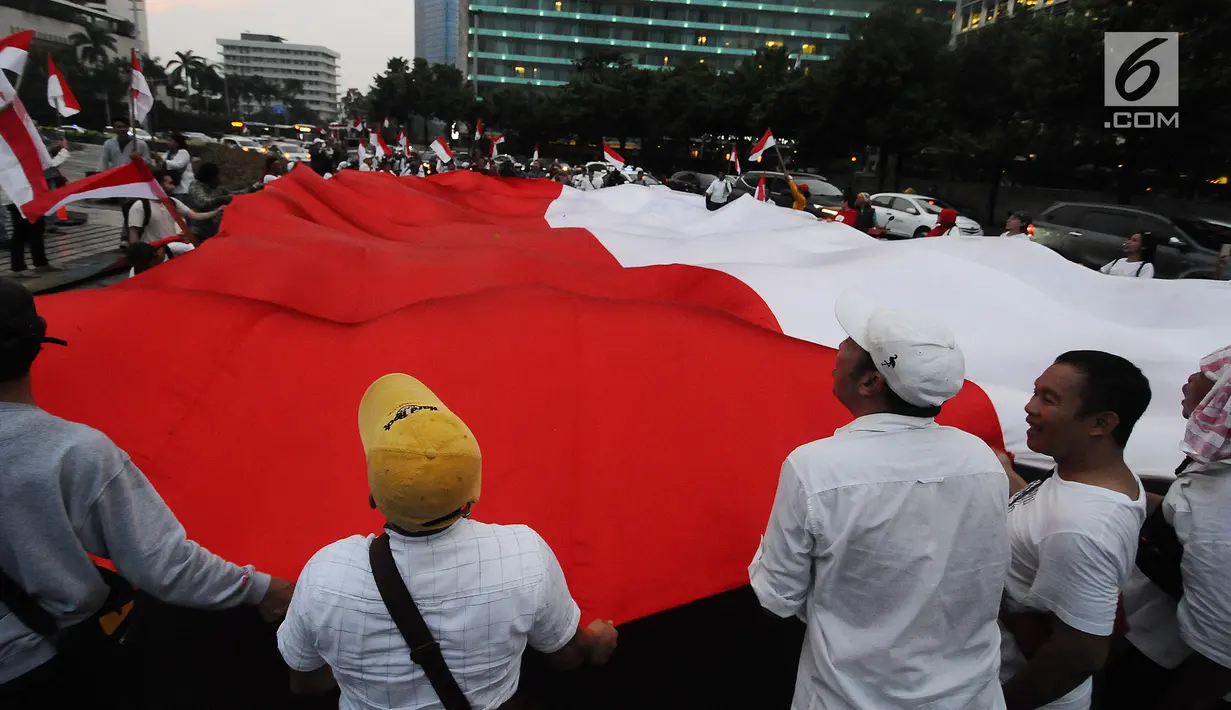 Sejumlah pendukung capres-cawapres 01 Jokowi-Ma'ruf Amin membentangkan bendera merah putih di kawasan bunderan HI, Jakarta, Rabu (17/4). Pendukung capres-cawapres 01 arak-arakan merayakan unggul dalam versi hitungan cepat. (Liputan6.com/Herman Zakharia)