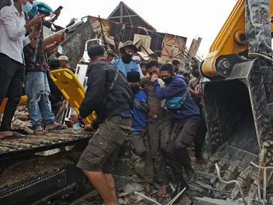 Tim penyelamat membantu korban yang ditarik keluar dari reruntuhan gedung pemerintah yang runtuh saat gempa bumi di Mamuju, Sulawesi Barat, Jumat (15/1/2021). Gempa bermagnitudo 6,2 mengguncang Mamuju, Sulawesi Barat. (AP Photo/Azhari Surahman)