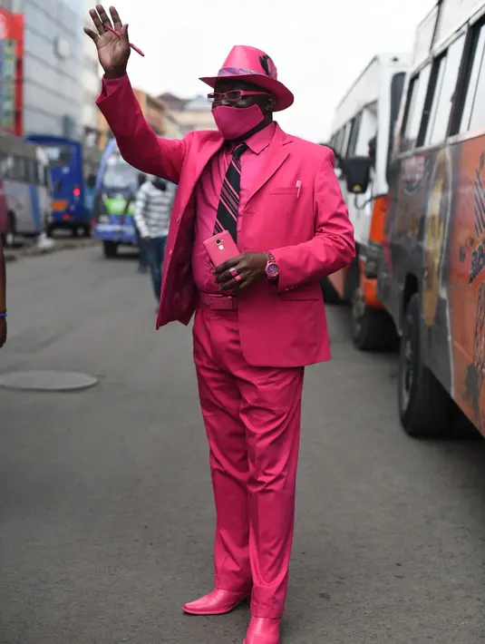Fashionista Kenya, James Mwangi Maina berjalan-jalan sambil memamerkan setelan jasnya yang senada dengan pakaian dan aksesorisnya, termasuk masker di Nairobi, 5 Agustus 2020. Mwangi mengklaim dirinya memiliki penampilan terbaik dan paling stylish di Afrika. (Simon MAINA/AFP)