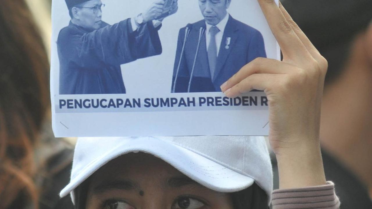 Pengunjuk rasa mengangkat poster bergambar Presiden Joko Widodo dengan tulisan: "Diberi amanah malah serakah." Foto: Merdeka.com/Imam Buhori