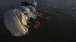 Para perempuan melarung persembahan dalam ritual untuk dewi laut Afrika Yemanja di Pantai Ramirez di Montevideo, Uruguay, Rabu (2/2/2022). Para pemuja mendatangi pantai pada pada hari raya Yemanja, membawa lilin, bunga, madu dan buah untuk menghormati dewi laut. (AP Photo/Matilde Campodonico)