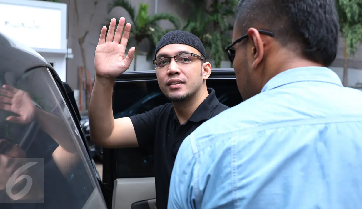 Sandy Tumiwa melambaikan tangan saat akan meninggalkan Kejaksaan Tinggi (Kejati) DKI Jakarta, Senin (7/11). Kedatangan Sandy untuk melakukan tahapan I, mengambil surat pengantar untuk dilimpahkan ke Kejaksaan Negeri Jakpus. (Liputan6.com/Herman Zakharia)