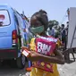Seorang gadis pergi dengan makanan ringan setelah memberikan sampel swab untuk menguji virus corona Covid-19 di dalam sebuah van di New Delhi, India (1/7/2021).  Kegiatan ini diselenggarakan oleh Polisi Delhi bekerja sama dengan lab Star Imaging and Path. (AFP/Prakash Singh)