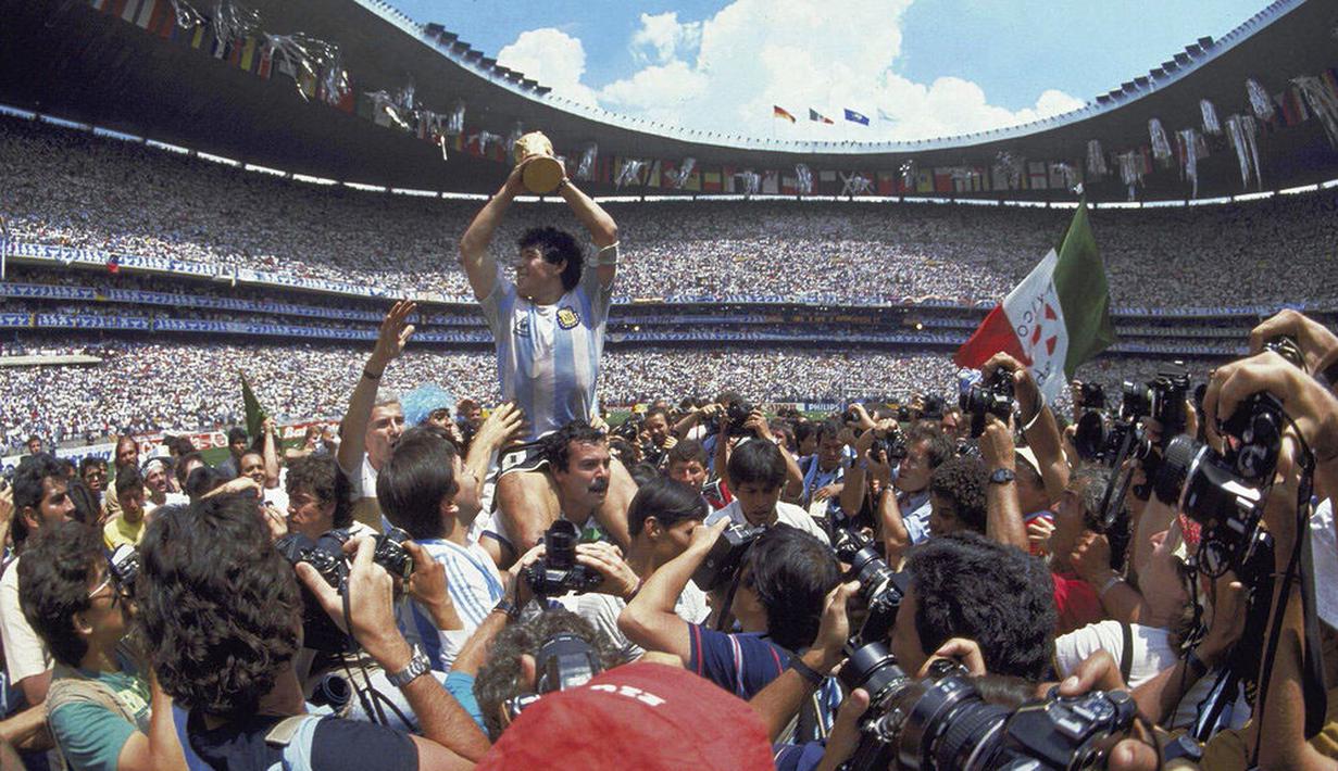 Penyerang Argentina, Diego Maradona, mengangkat trofi Piala Dunia saat usai mengalahkan Jerman Barat pada laga final Piala Dunia 1986 di Meksiko, (29/6/1986). (Photo by - / AFP)