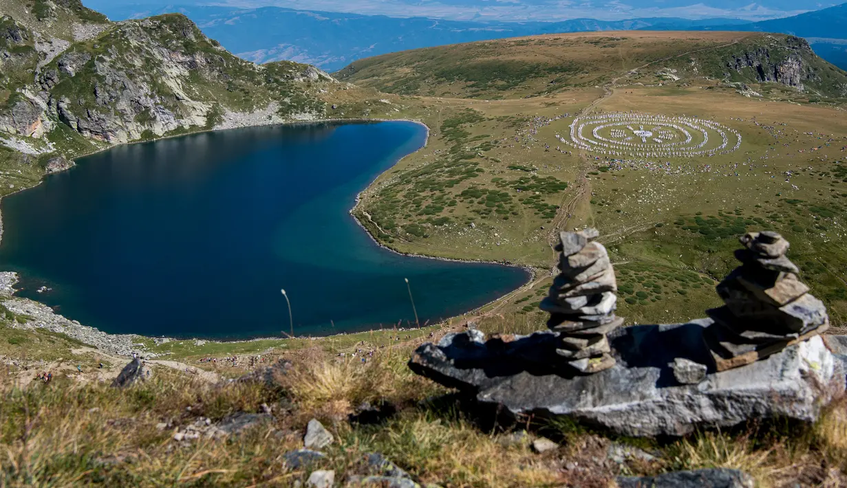 Anggota gerakan keagamaan internasional White Brotherhood menari di puncak Gunung Rila, Bulgaria, Senin (19/8/2019). White Brotherhood dilarang selama komunisme dan masih dianggap sebagai sekte oleh Gereja Ortodoks Kristen di negara itu. (NIKOLAY DOYCHINOV/AFP)