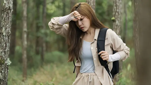 Seorang perempuan tampak memegang dahinya ketika sedang mendaki (Foto Dok: Freepik/EyeEm)