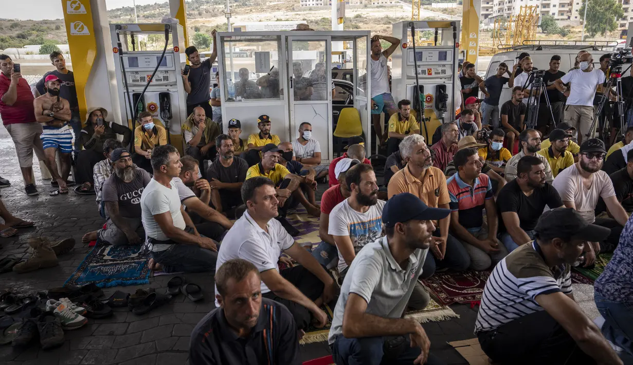 Umat Muslim mendengarkan khotbah selama salat Jumat di sebuah pompa bensin di kota pesisir Jiyeh, selatan Beirut, Lebanon, Jumat (3/9/2021). Puluhan jemaah berlutut dalam salat Jumat di tengah ratusan mobil dan pengendara yang antre untuk mengisi mobilnya dengan bahan bakar. (AP Photo/ Hassan Ammar)