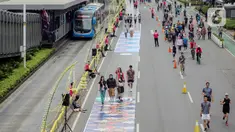 Sejumlah orang yang mengenakan batik berjalan di catwalk sepanjang Jalan Jenderal Sudirman, Jakarta, Minggu (2/10/2022). Kegiatan yang diikuti ratusan orang ini diselenggarakan oleh Bank Mandiri untuk menyambut Hari Batik Nasional yang jatuh setiap tanggal 2 Oktober 2022. (Liputan6.com/Faizal Fanani)