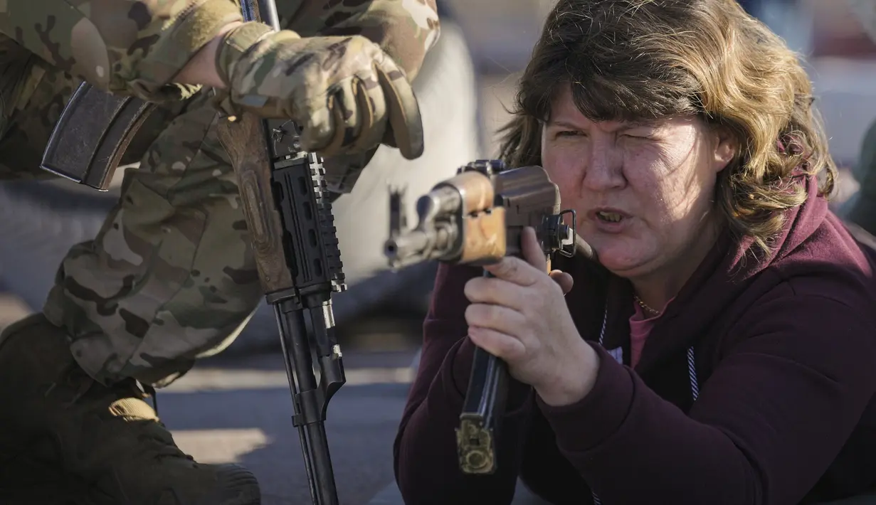 Seorang wanita memegang senjata selama pelatihan perang dasar untuk warga sipil oleh Unit Pasukan Khusus Azov, dari Garda Nasional Ukraina, di Mariupol, wilayah Donetsk, Minggu (13/2/2022). Mereka disiapkan untuk bisa bertahan di tengah kekhawatiran akan invasi Rusia. (AP Photo/Vadim Ghirda)