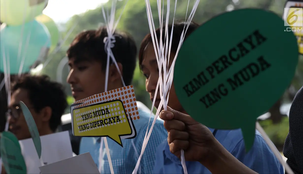 Aktivis Poros Indonesia Muda saat melakukan aksi dengan membawa balon bertempelkan gambar politisi muda di Gedung KPU, Jakarta, Rabu (1/8). Mereka berharap Pemilu 2019 mendapatkan pilihan yang membawa aspirasi kaum muda. (Liputan6.com/Helmi Fithriansyah)