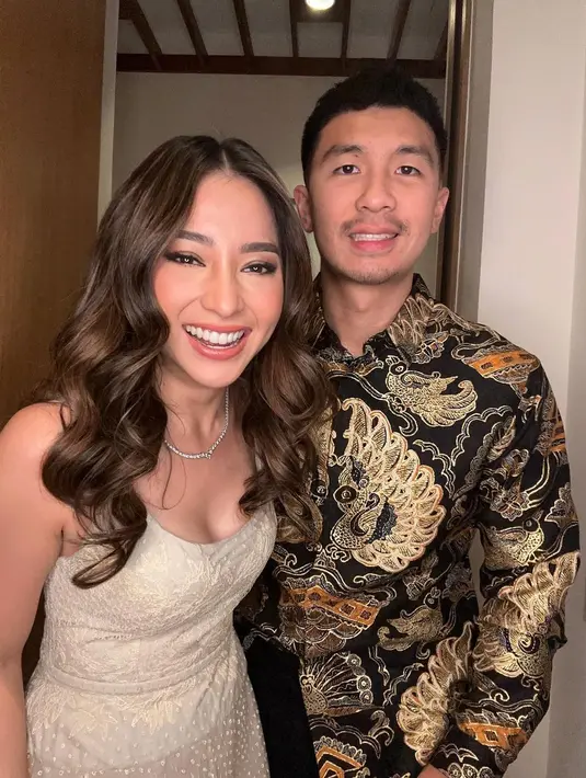 Outfit kompak Nikita Willy dan Indra Priawan saat kondangan. Keduanya tampak serasi dengan busana nuansa keemasan.