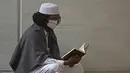 Seorang pria Muslim yang mengenakan masker wajah membaca Alquran di Masjid Agung Faisal pada awal Itikaf, di sebuah masjid untuk pria selama bulan suci Ramadhan di Islamabad (3/5/2021). (AFP/Aamir Qureshi)