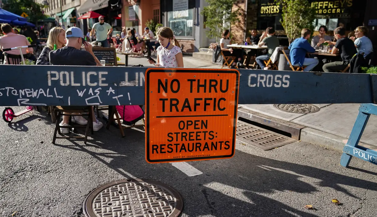 Pengunjung duduk di luar restoran yang mengoperasikan area luar ruangan (outdoor) hingga ke trotoar dan jalanan di New York pada 3 Oktober 2020. Kota tersebut mengizinkan restoran membuat area makan outdoor sebagai upaya mengatasi dampak ekonomi COVID-19 yang berkelanjutan. (AP Photo/John Minchillo)