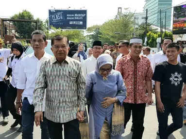 Mantan Wakil Presiden Jusuf Kalla atau JK (kiri) didampingi istrinya Mufidah berjalan kaki saat tiba di kampung halamannya, Makassar, Sulawesi Selatan, Sabtu (26/10/2019). JK disambut meriah warga Makassar. (Liputan6.com/HO/Tim JK)