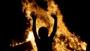 Warga menari di dekat kobaran api saat mengikuti tradisi malam San Juan's (Saint John) di Gijon, Spanyol, (24/6). Malam San Juan adalah upacara penyucian dimana warga membakar sejumlah benda yang sudah tidak diinginkan. (REUTERS/Eloy Alonso)