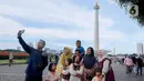 Warga berswafoto saat berwisata di kawasan Monumen Nasional (Monas), Jakarta, Sabtu (5/4/2025). (Liputan6.com/Herman Zakharia)