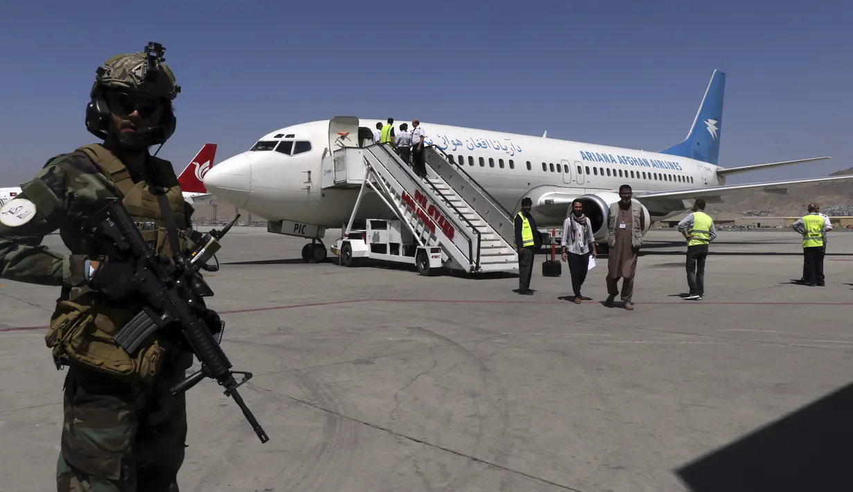 Seorang tentara Taliban berjaga-jaga ketika penumpang turun dari Kandahar, di Bandara Internasional Hamid Karzai di Kabul, Afghanistan, Minggu (5/9/2021). Bandara tersebut kembali dibuka untuk penerbangan domestik. (AP/Wali Sabawoon)