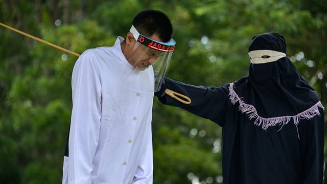 <span>Salah seorang pasangan terpidana kasus zina (kiri) menjalani hukuman cambuk di Masjid Al Munawarah, Kota Jantho, Aceh Besar, Jumat (4/9/2020). Pasangan terpidana yang terbukti melanggar Syariat Islam dalam kasus zina itu masing masing menjalani sebanyak 100 cambuk. (CHAIDEER MAHYUDDIN/AFP)</span>