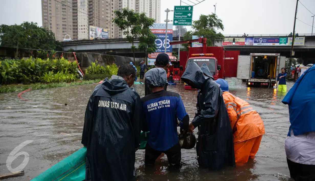 Petugas dari Suku Dinas Tata Air memasang mesin pompa untuk menyedot air banjir yang merendam Jalan Gunung Sahari, Jakarta, Selasa (21/2). Hujan yang mengguyur sejak Selasa dinihari membuat sebagian wilayah di Jakarta banjir. (Liputan6.com/Faizal Fanani)