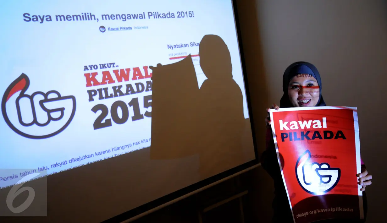 Aktivis Koalisi KawalPilkada mengangkat poster usai memberikan pernyataan kepada wartawan di Gedung KPU Pusat, Jakarta, Senin (9/11/2015). Koalisi KawalPilkada mengembangkan website untuk mengawal proses Pilkada. (Liputan6.com/Helmi Fithriansyah)