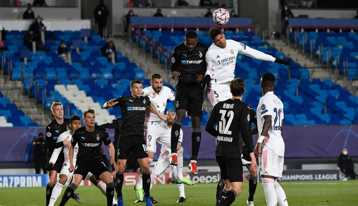 Bek Real Madrid, Raphael Varane (kanan) berusaha menyundul bola saat bertanding melawan Borussia Monchengladbach pada Grup B Liga Champions di Estadio Alfredo Di Stefano, Kamis (10/12/2020). Kemenangan ini mengantar Madrid lolos ke babak 16 besar Liga Champions. (AFP/PIERRE-PHILIPPE MARCOU)
