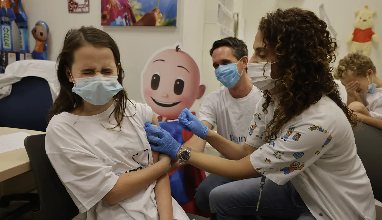 Reaksi Noa Bershadsky (11) bereaksi ketika disuntik vaksin COVID-19 dan saudara laki-lakinya, Ori, menutupi matanya di layanan Clalit Health di Holon, Israel, Senin (22/11/2021). Israel pada Senin mulai menyuntikkan vaksin Covid-19 pada anak usia 5 hingga 11 tahun. (AP Photo/Tsafrir Abayov)