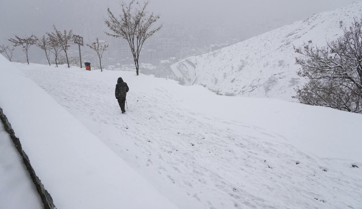 Seorang pria berjalan turun di Kompleks Olahraga dan Rekreasi Tochal yang bergunung-gunung saat salju turun, di utara Teheran, Iran (24/12/2022). Salju dan hujan membawa kebahagiaan bagi banyak orang yang khawatir kekurangan air di Iran, negara yang telah mengalami kekeringan selama beberapa dekade. (AP Photo/Vahid Salemi)