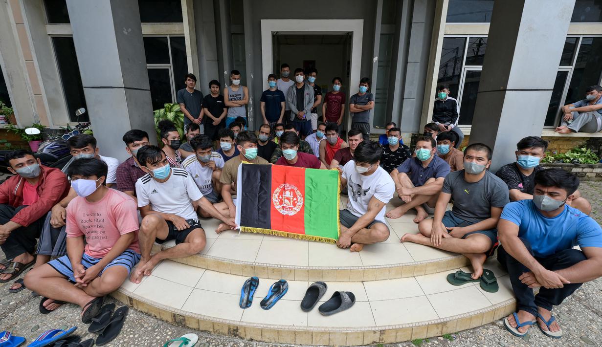 Pengungsi Afghanistan mengibarkan bendera negaranya untuk menunjukkan identitasnya di sebuah kamp pengungsi di Bekasi, Jawa Barat (20/8/2021). Mereka tidak bersedia kembali ke negaranya, terutama setelah Taliban mengambil alih kekuasaan dari pemerintahan Presiden Ashraf Ghani. (AFP/Bay Ismoyo)