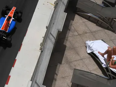Pebalap Manor Racing, Pascal Wehrlein, melintas di dekat seorang turis yang sedang berjemur sambil menyaksikan latihan bebas F1 GP Monako di sirkuit jalan raya Monako. (AFP/Pascal Guyot)