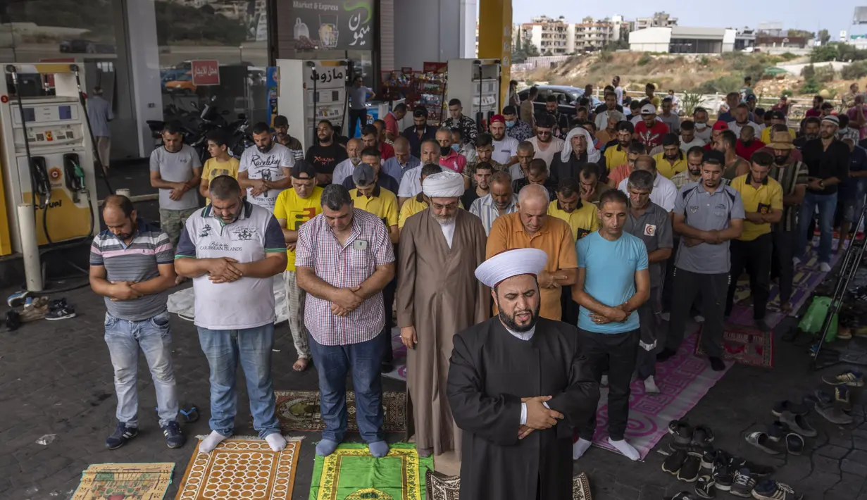 Umat Muslim melaksanakan salat Jumat di sebuah pompa bensin di kota pesisir Jiyeh, selatan Beirut, Lebanon, Jumat (3/9/2021). Sholat Jumat digelar di Pom Bensin ketika Lebanon terus bergulat dengan kekurangan bahan bakar yang menyesakkan. (AP Photo/ Hassan Ammar)