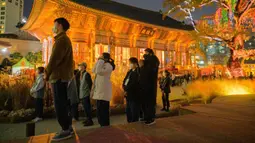 Warga berdoa di Kuil Jogyesa pada malam sebelum para siswa mengikuti ujian masuk universitas atau suneung, Seoul, Korea Selatan, 17 November 2021. Lebih dari setengah juta siswa akan mengikuti suneung di Korea Selatan. (Anthony WALLACE/AFP)