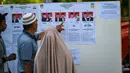 Melalui Pilkada, para pemimpin daerah yang dipilih langsung oleh rakyat diharapkan bekerja lebih maksimal dalam menjalankan tugas dan meningkatkan kesejahteraan masyarakat. Tampak dalam foto, calon pemilih memeriksa kandidat sebelum memberikan suara mereka dalam pemilihan eksekutif lokal di Darul Imarah, pinggiran Banda Aceh pada 27 November 2024. (CHAIDEER MAHYUDDIN/AFP)