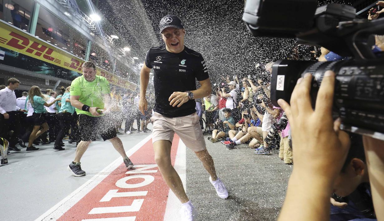 Pebalap Mercedes, Valtteri Bottas saat merayaka keberhasilan meraih podium pada balapan F1 Singapura di Marina Bay City Circuit Singapore, (17/9/2017). Bottas finis ketiga pada balapan tersebut. (AP/Yong Teck Lim)