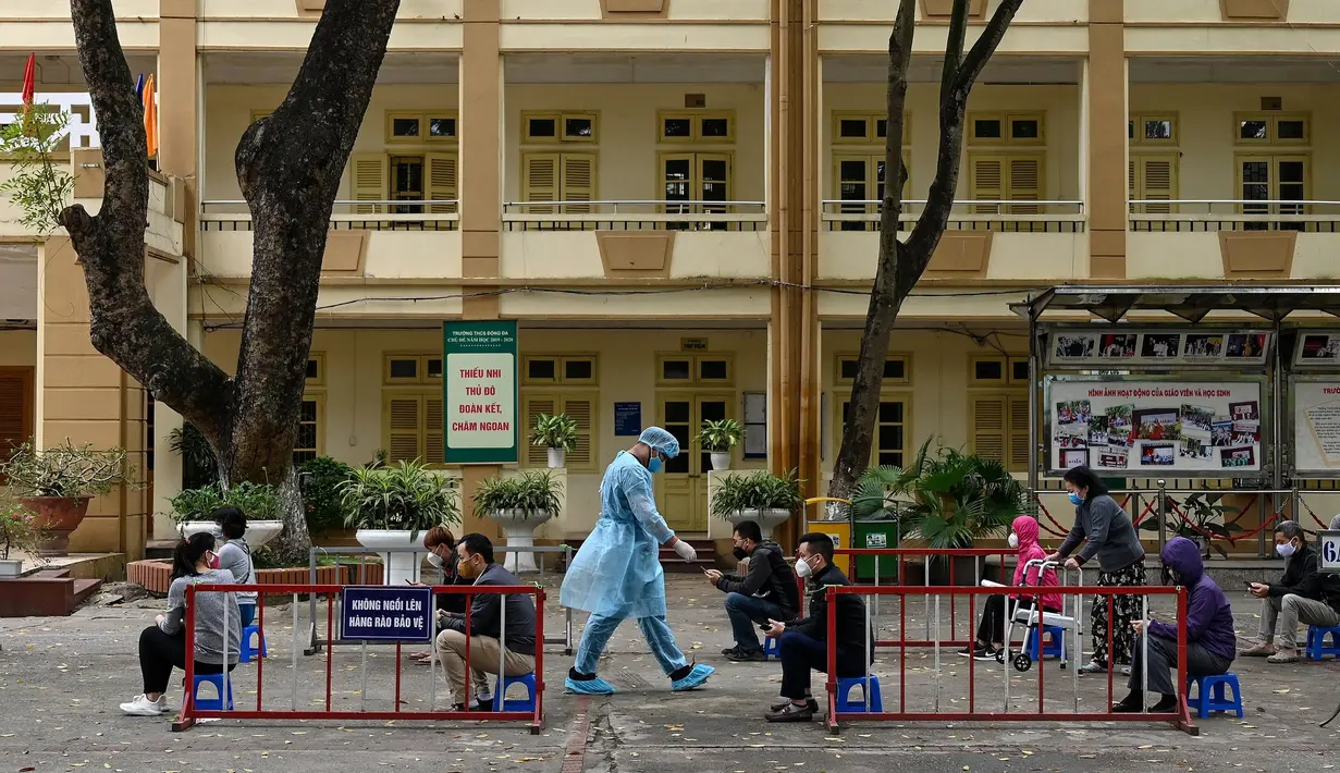 Penduduk memakai masker mengantre dengan tertib saat akan mengikuti pengujian Covid-19 di pusat pengujian darurat di Hanoi, Vietnam (31/3/2020). Di pusat pengujian darurat ini petugas menyediakan fasilitas bangku kecil yang diberi jarak untuk pencegahan Covid-19. (AFP/Manan Vatsyayana)