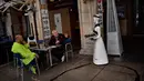 Sebuah robot yang dikenal sebagai "Alexia" mendatangi pelanggan sebuah bar di alun-alun Plaza del Castillo, di Pamplona, Spanyol pada 5 Juni 2020. Robot tersebut digunakan untuk mengurangi penyebaran virus corona Covid-19. (AP Photo/Alvaro Barrientos)